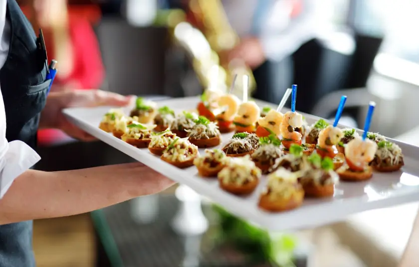 Catering tray with assorted appetizers, including shrimp and bruschetta, at an event.
