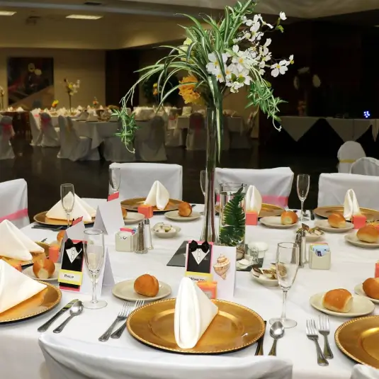 Elegant wedding reception table setting with gold plates and floral centerpiece