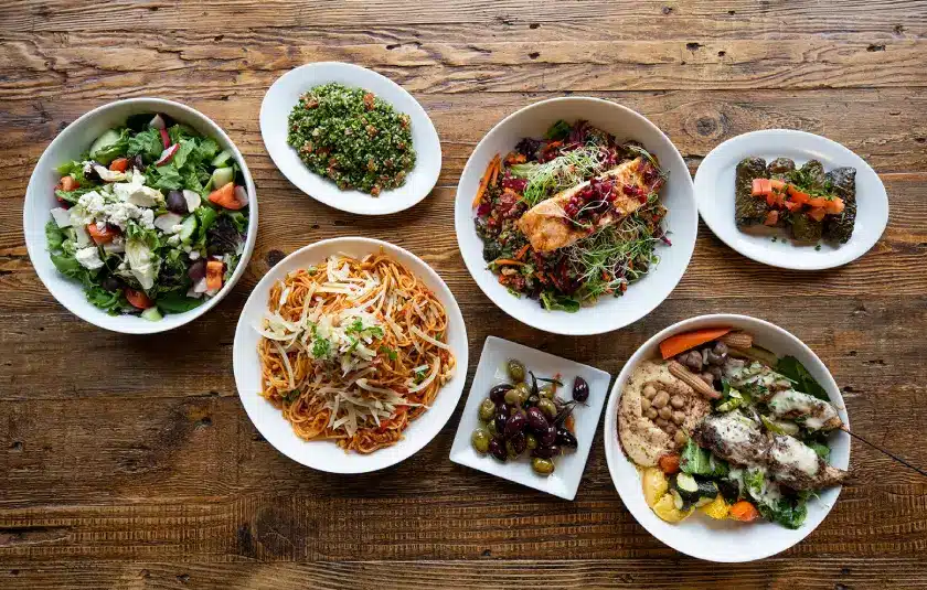 Overhead view of a rustic wooden table laden with a diverse spread of Mediterranean dishes.