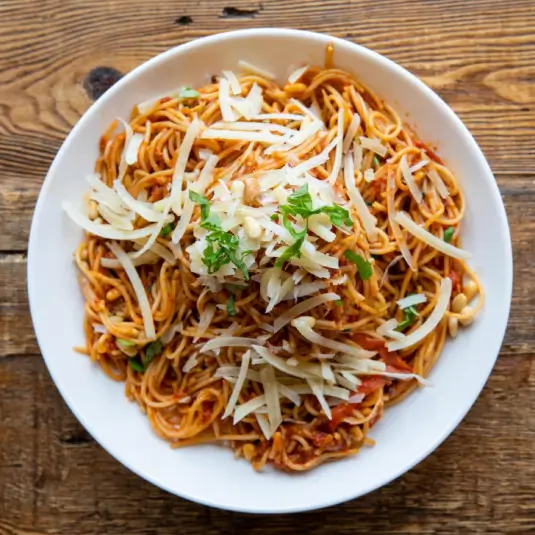 Spaghetti with tomato sauce and grated cheese in a white bowl